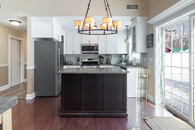 kitchen with sink, stainless steel appliances, light stone countertops, a kitchen island, and decorative light fixtures