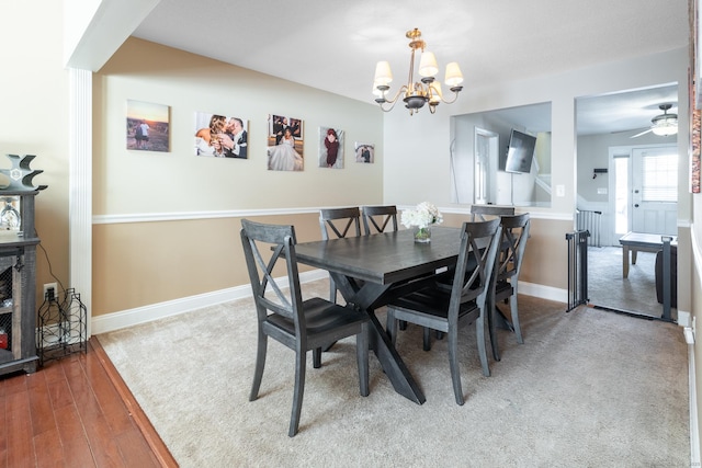 dining area with ceiling fan with notable chandelier and hardwood / wood-style floors