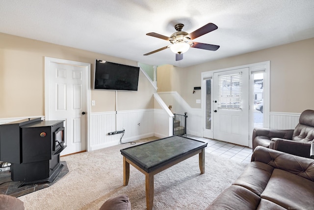 living room featuring ceiling fan, light tile patterned floors, a textured ceiling, and a wood stove