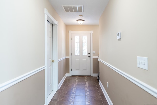 doorway featuring a textured ceiling and dark tile patterned floors