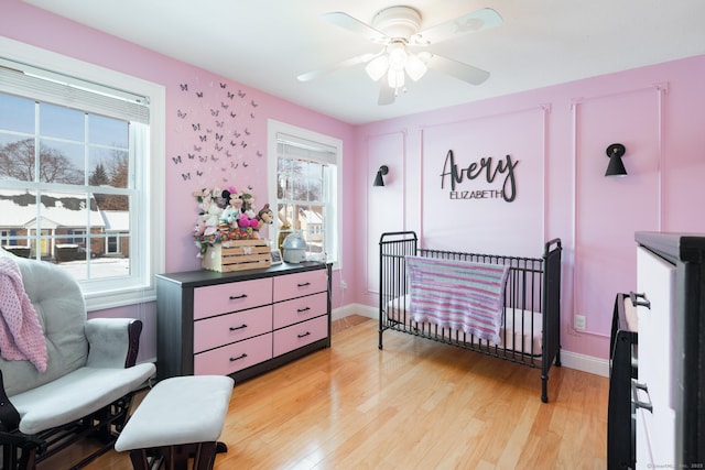 bedroom with a crib, ceiling fan, and light hardwood / wood-style floors