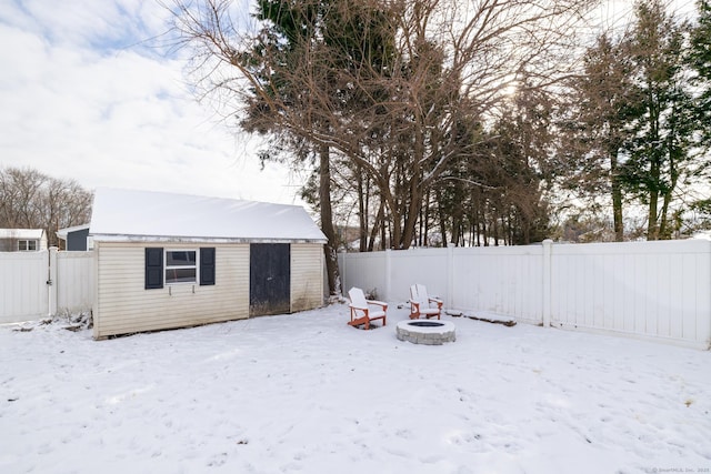 snowy yard featuring an outbuilding and an outdoor fire pit