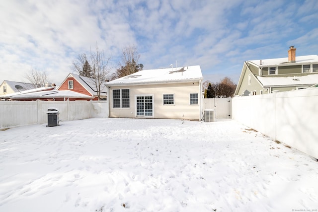 snow covered back of property featuring central AC unit