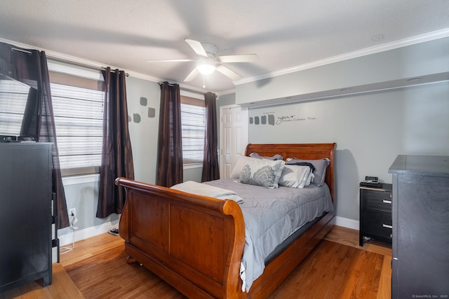 bedroom featuring hardwood / wood-style flooring, crown molding, ceiling fan, and multiple windows