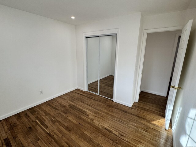 unfurnished bedroom with dark hardwood / wood-style floors and a closet