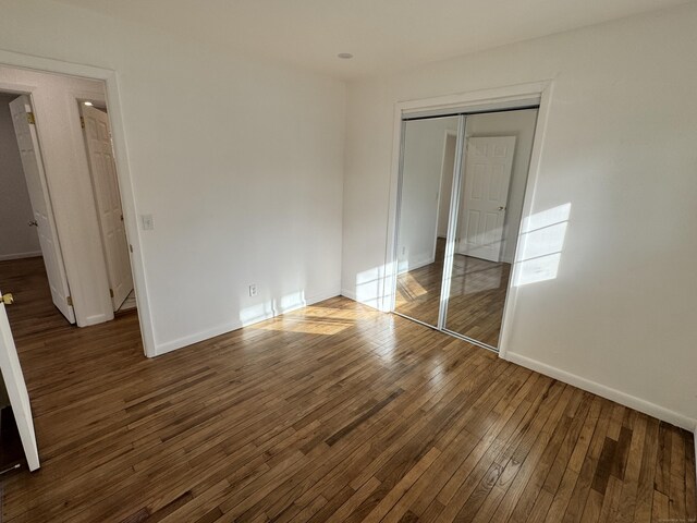 unfurnished bedroom featuring dark hardwood / wood-style flooring and a closet