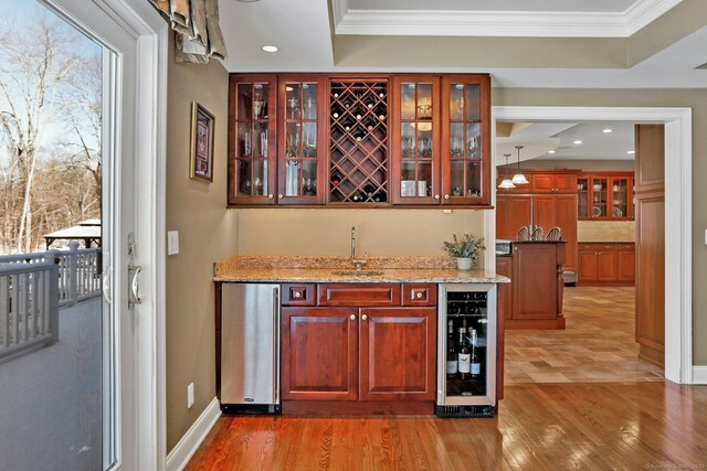 bar featuring sink, fridge, wine cooler, light stone countertops, and ornamental molding