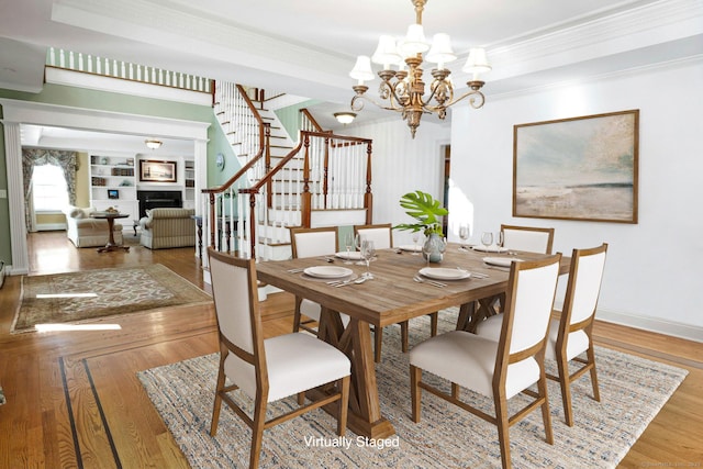 dining space with crown molding, wood-type flooring, and a notable chandelier