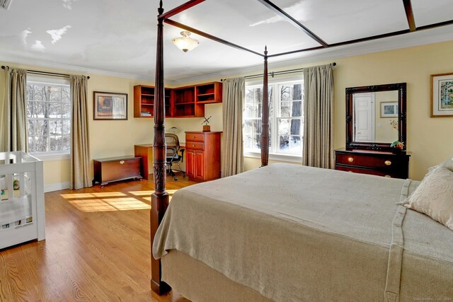 bedroom featuring multiple windows, crown molding, and light hardwood / wood-style flooring