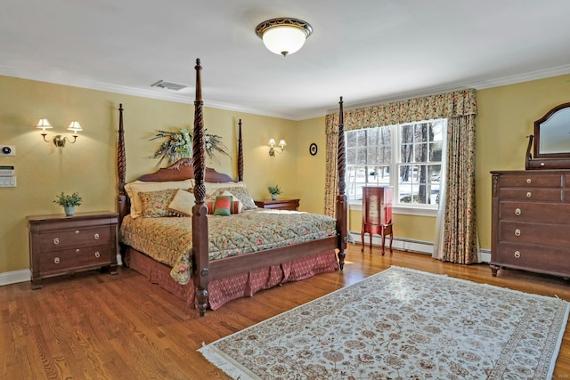 bedroom with hardwood / wood-style flooring, crown molding, and baseboard heating