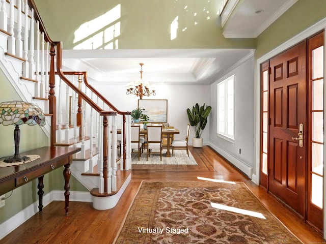 entrance foyer featuring hardwood / wood-style flooring, crown molding, and an inviting chandelier