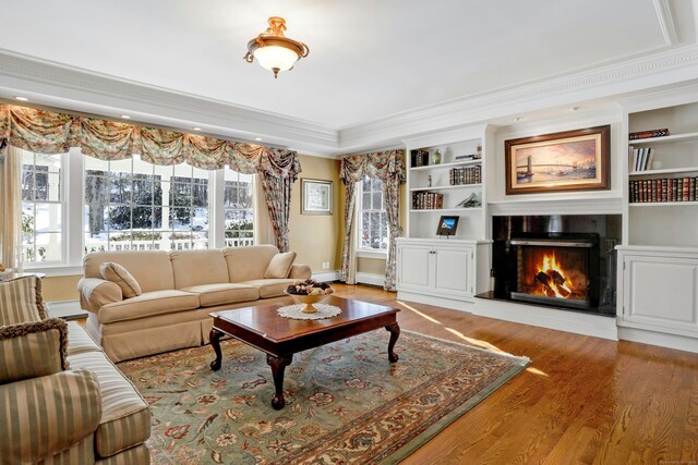 living room with crown molding, built in features, and light hardwood / wood-style flooring