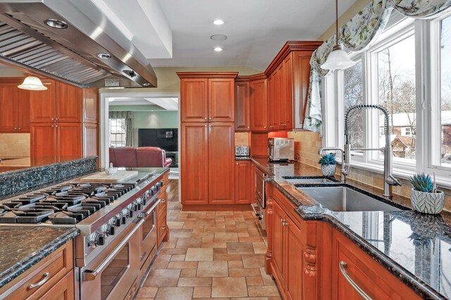 kitchen with double oven range, island range hood, decorative light fixtures, and dark stone counters