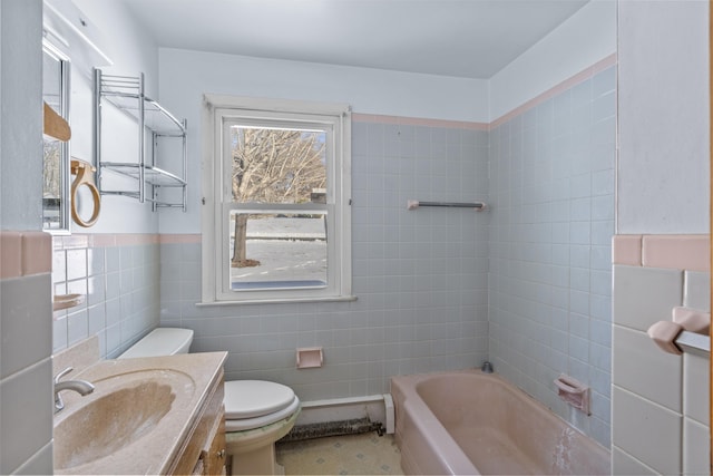 bathroom with tile walls, vanity, a washtub, and toilet