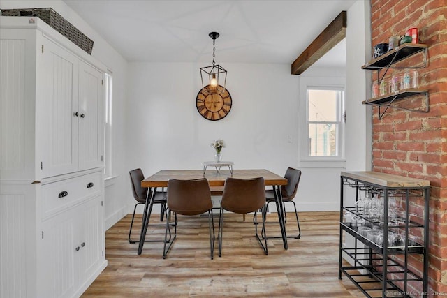 dining area featuring beamed ceiling and light hardwood / wood-style flooring