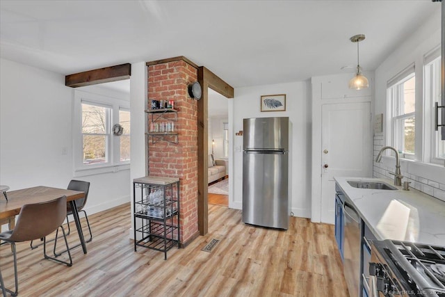 kitchen with appliances with stainless steel finishes, light stone countertops, sink, and plenty of natural light