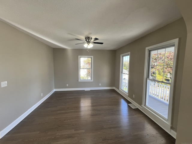 empty room with dark hardwood / wood-style floors, a textured ceiling, and ceiling fan