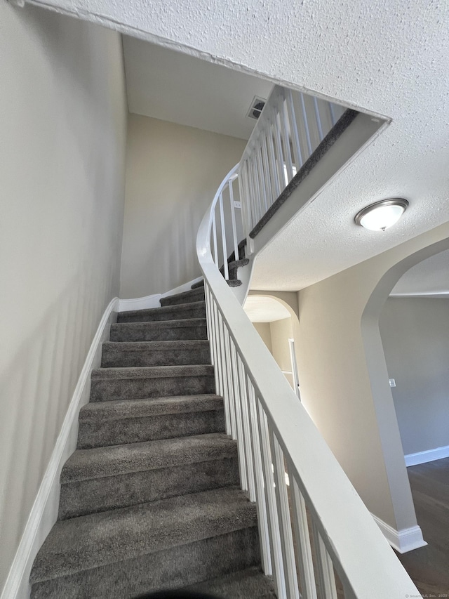 stairway featuring hardwood / wood-style floors and a textured ceiling