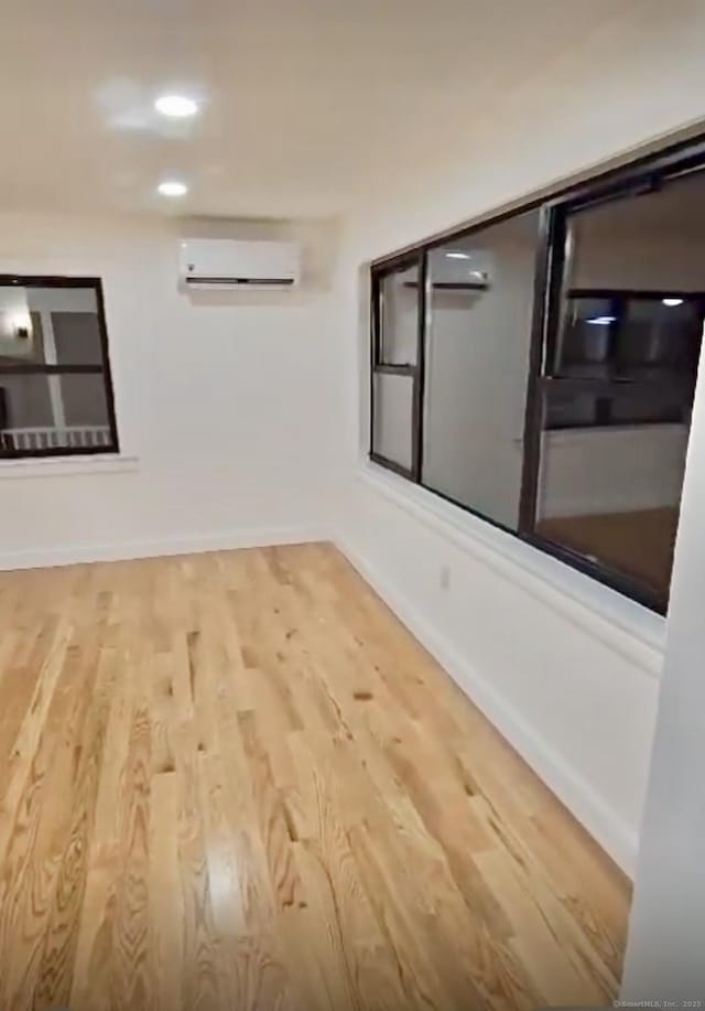 unfurnished room featuring wood-type flooring and an AC wall unit