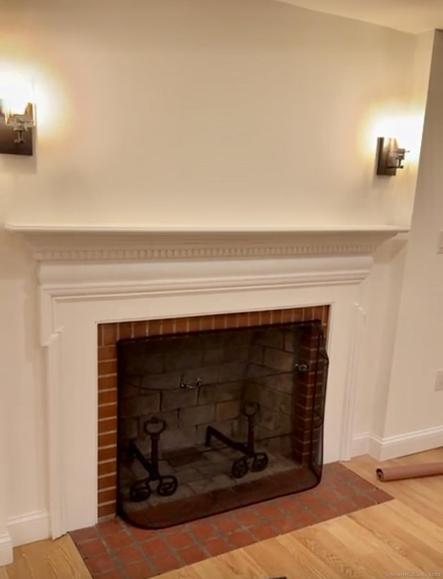 details with wood-type flooring and a brick fireplace