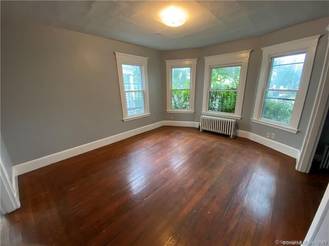 spare room with radiator heating unit and dark hardwood / wood-style flooring