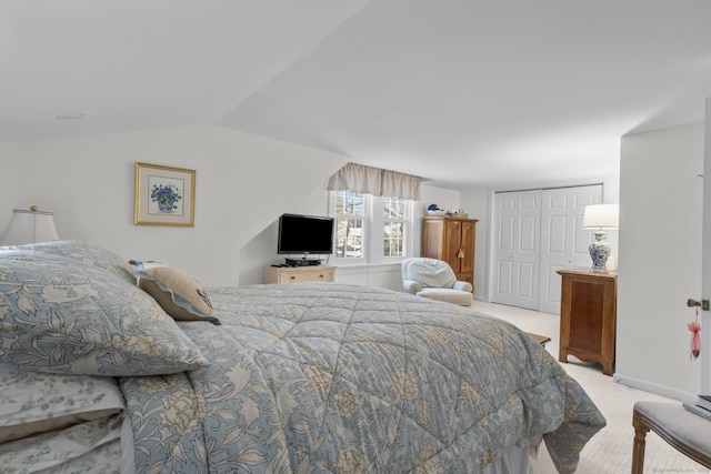 bedroom with vaulted ceiling, light colored carpet, and a closet