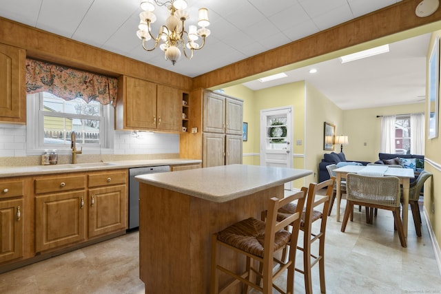 kitchen featuring stainless steel dishwasher, a healthy amount of sunlight, sink, and a kitchen island