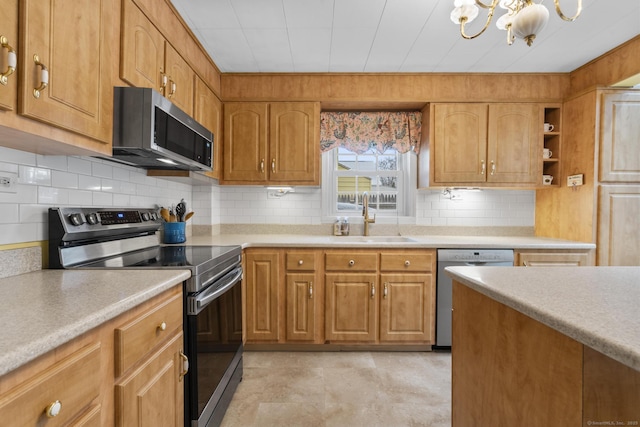 kitchen with appliances with stainless steel finishes, sink, a notable chandelier, and decorative backsplash