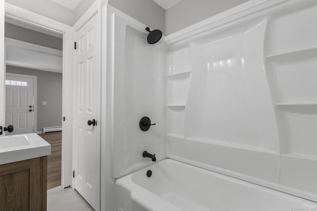 bathroom with washtub / shower combination, vanity, and a baseboard heating unit