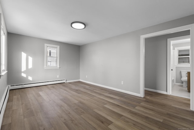 spare room with hardwood / wood-style floors and a baseboard heating unit