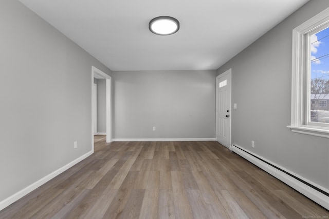 spare room with a baseboard heating unit and light hardwood / wood-style flooring