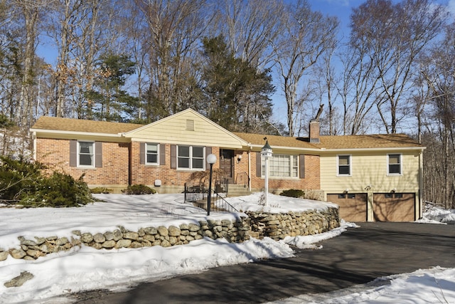 ranch-style house with driveway, a garage, a chimney, and brick siding