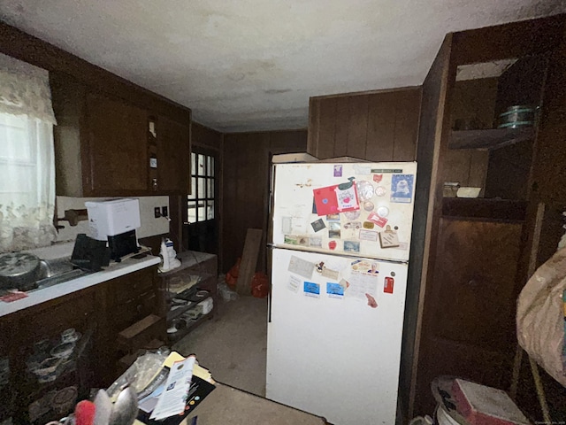 kitchen featuring dark brown cabinetry, concrete floors, and white fridge