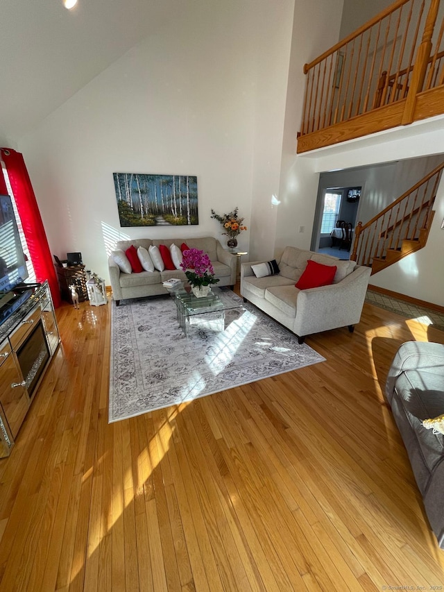 living room featuring high vaulted ceiling and light wood-type flooring