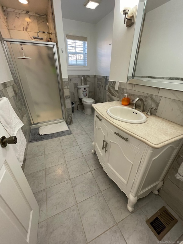 bathroom featuring tile walls, vanity, an enclosed shower, tile patterned floors, and toilet