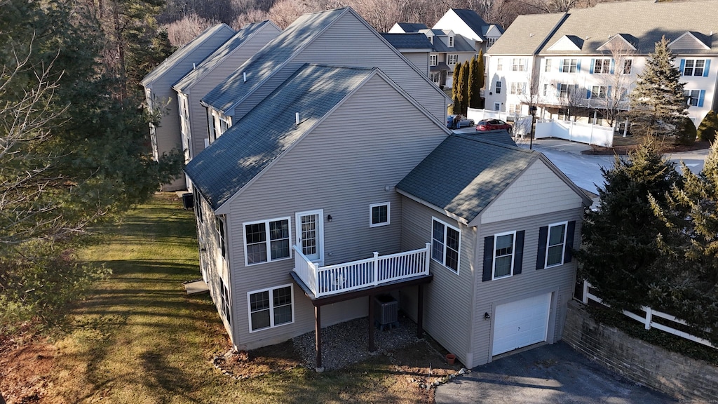 exterior space with a garage, a deck, central AC unit, and a lawn