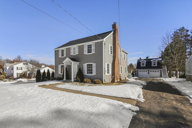 view of front of house featuring an outdoor structure, a chimney, and a detached garage