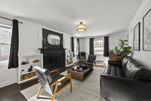 living area with visible vents, a fireplace with flush hearth, ornamental molding, wood finished floors, and baseboards