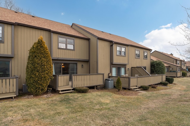 rear view of property with cooling unit, a deck, and a lawn