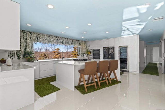 kitchen featuring a kitchen breakfast bar, light tile patterned floors, a kitchen island, and white cabinets