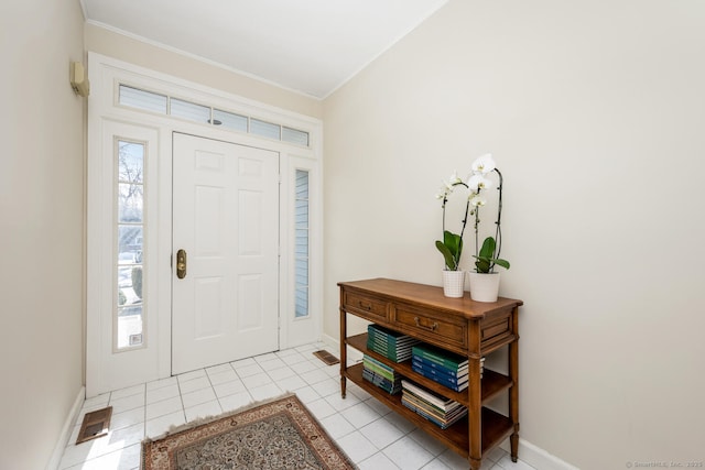 tiled entryway featuring crown molding