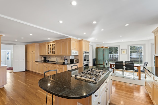 kitchen with recessed lighting, stainless steel appliances, a sink, light wood-style floors, and glass insert cabinets