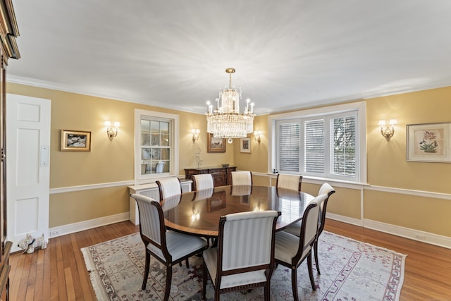 dining room with crown molding, a notable chandelier, hardwood / wood-style flooring, and baseboards