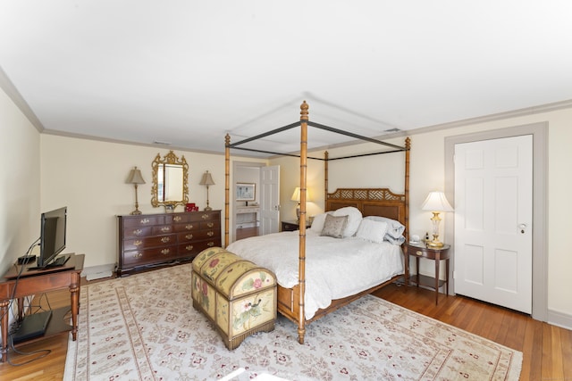 bedroom with ornamental molding, baseboards, and hardwood / wood-style flooring