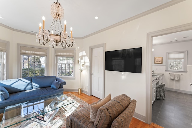 living room with baseboards, light wood-style flooring, ornamental molding, an inviting chandelier, and recessed lighting