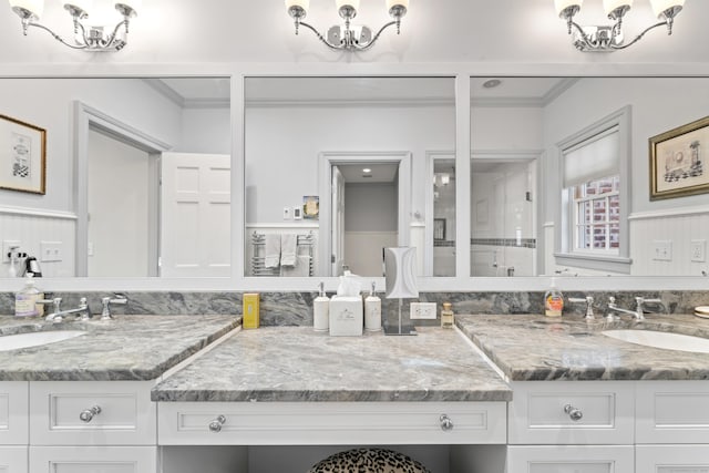 bathroom with an inviting chandelier, ornamental molding, and vanity