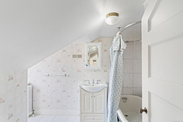 full bathroom featuring visible vents, lofted ceiling, tile patterned floors, vanity, and tile walls