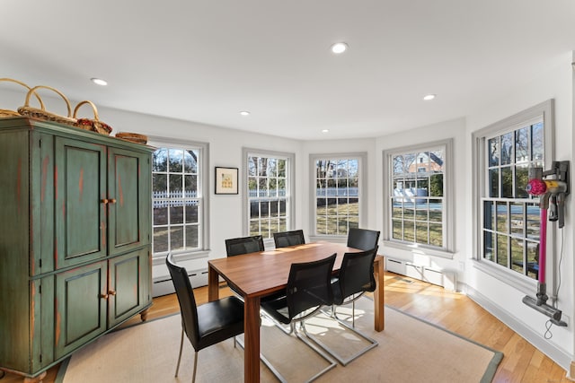 dining area with light wood finished floors, a baseboard radiator, a wealth of natural light, and recessed lighting