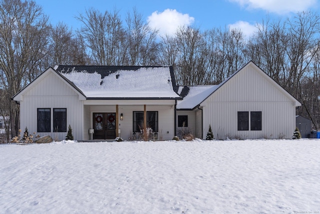 snow covered back of property with covered porch