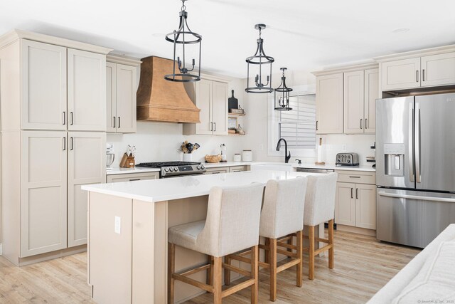 kitchen with sink, a center island, light hardwood / wood-style floors, stainless steel appliances, and custom range hood